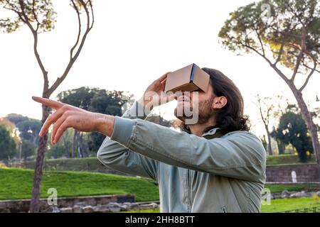 The young man in Rome observes a virtual reconstruction with a cardboard viewer. The man they look into the viewer makes a journey through time and sp Stock Photo