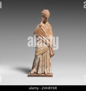 Terracotta statuette of a draped woman 3rd century B.C. Greek, Boeotian Standing, draped, enveloped in himation.. Terracotta statuette of a draped woman. Greek, Boeotian. 3rd century B.C.. Terracotta. Hellenistic. Terracottas Stock Photo