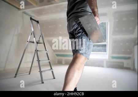 Man plastering drywall in a private house. Stock Photo