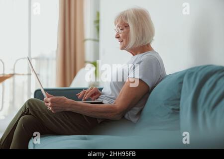 Modern old lady using laptop computer at home Stock Photo