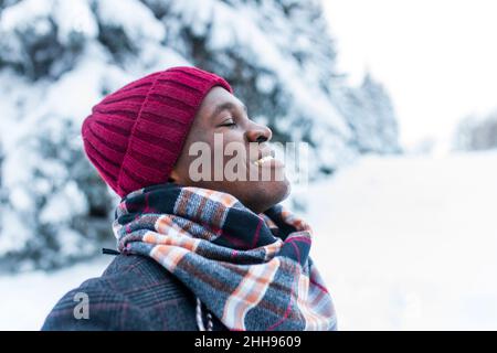 happy carefree african american man in warm clothes taking a deep breath in fir forest Stock Photo