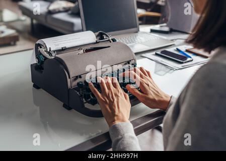 Woman author composes text on a typewriter sitting in her working room Stock Photo