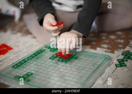Hands of little caucasian boy playing a board game on the floor in her room,lifestyle toned photo at home Stock Photo