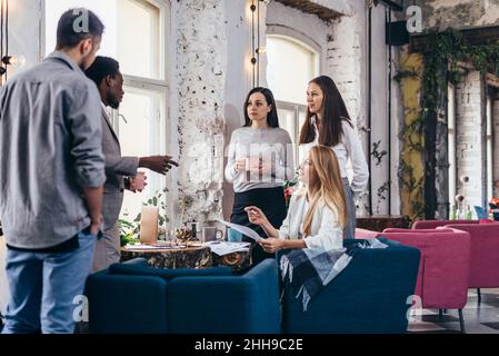 Group of people gathered around table during break in a coffee shop. Stock Photo