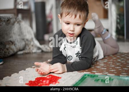 Little caucasian boy playing a board game on the floor in her room,lifestyle toned photo at home Stock Photo