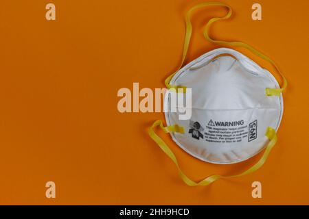 N95 face respirator face mask on a bright orange background with copy space