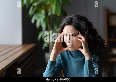 Concerned female having anxious thoughts, stressed young woman suffering from anxiety headache Stock Photo