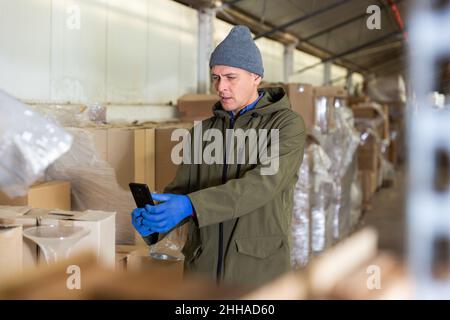 Warehouse worker using his smartphone to take photographs Stock Photo