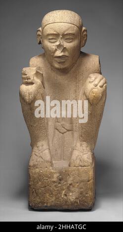 Standard Bearer 15th–early 16th century Aztec Wearing a simple loincloth tied in front in a prominent knot, this strong male figure is seated on a massive block. The elaborate lashings of his sandals suggest that he is an individual belonging to a high social class, since commoners in Aztec society went mostly barefoot. The facial contours are rounded and soft, and there is a slight frown on the forehead; his mouth is half open as if speaking. His almond-shaped eyes once held inlays. The curved, deeply grooved line across the top of the face indicates the hairline, but the head itself is smoot Stock Photo