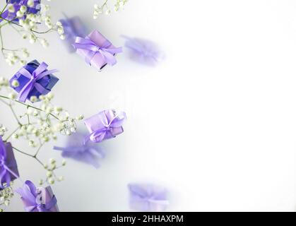 A multi-layered postcard made of gift boxes in a fashionable, trendy very peri color with white flowers on a foggy background. Happy women day and Val Stock Photo