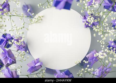 A multi-layered postcard made of gift boxes in a fashionable, trendy very peri color with white flowers on a foggy background. Happy women day and Val Stock Photo