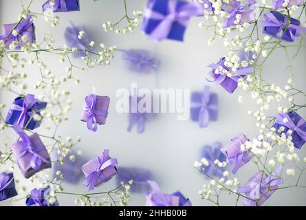 A multi-layered postcard made of gift boxes in a fashionable, trendy very peri color with white flowers on a foggy background. Happy women day and Val Stock Photo