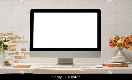 Modern office desk with pc desktop computer white screen display, office supplies, decor on table over white brick wall. Stock Photo