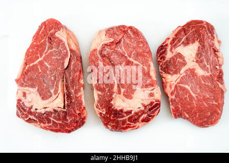 three raw Rib eye steaks on a white background. Food concept. overhead view. Stock Photo