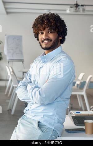 Portrait of happy smiling casual indian ethnic business man in boardroom Stock Photo