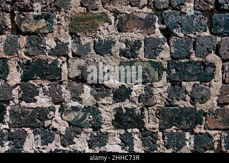 very old black brick wall with large cracks Stock Photo