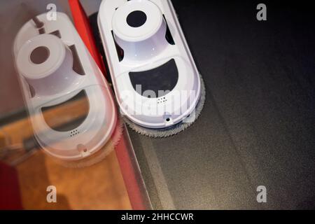 Downside of vacuum cleaner robot for washing glass window and remote control on grey background. Robot assistant at home for cleaning windows Stock Photo