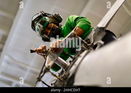 Usa. 7th Jan, 2022. Aviation Machinist's Mate 2nd Class Desiree Thomas, from Aurora, Colo., performs maintenance on an MH-60S Sea Hawk helicopter, assigned to the Chargers of Helicopter Sea Combat Squadron (HSC) 14, in the hangar bay aboard USS Abraham Lincoln (CVN 72). The Abraham Lincoln Carrier Strike Group, led by Carrier Strike Group 3, deployed from San Diego, Jan. 3, in support of global maritime security operations. An integral part of U.S. Pacific Fleet, U.S. 3rd Fleet operates naval forces in the Indo-Pacific and provides the realistic, relevant training necessary to flawlessly Stock Photo