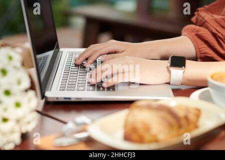 Hands of woman typing on laptop when writing articles for her school or local website Stock Photo