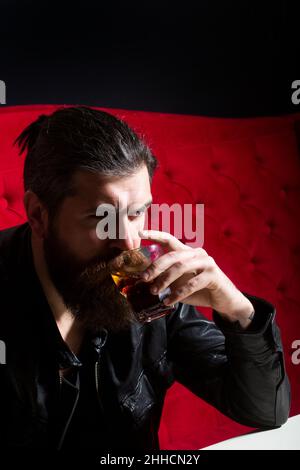Handsome stressed businessman in formal wear holding a glass of whiskey. Confident and handsome Brutal man. Hipster with beard and mustache drinks Stock Photo