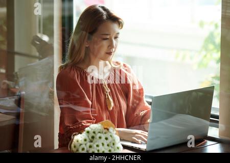 Young woman concentrated on working on laptop and checking her programming code Stock Photo