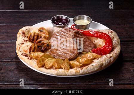 Delicious juicy chicken steak with baked potatoes, mushrooms and sauces on a white dish Stock Photo