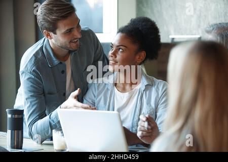 Smiling diverse colleagues gather in boardroom brainstorm discuss financial statistics together, happy multiracial coworkers have fun cooperating work Stock Photo