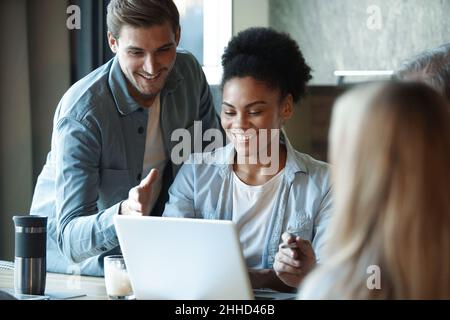 Smiling diverse colleagues gather in boardroom brainstorm discuss financial statistics together, happy multiracial coworkers have fun cooperating work Stock Photo
