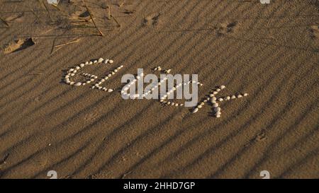 with shells laid symbol happiness on the beach of the Baltic Sea in the sand. Wishes for the vacation and life. Stock Photo