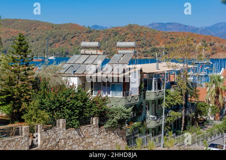 A lot of solar water heating systems on roof of cottage. A lot of large water tanks and solar panels on roof. Stock Photo