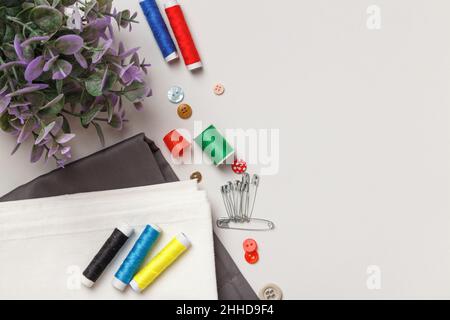 Sewing tools and accessories. Fabric thread plant flower on a gray background. Top view flat copy space Stock Photo