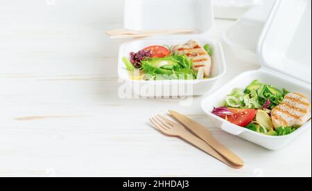 Food delivery of lunch boxes with salad on white wooden background. Copy space. Stock Photo