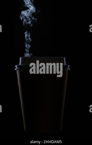 Illuminated edges of the silhouette of a disposable cup on black background for hot coffee and hot drinks with steam escaping. Stock Photo