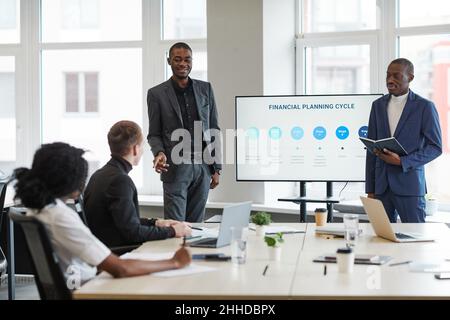 Portrait of young African-American woman speaking to colleague during business meeting in office Stock Photo