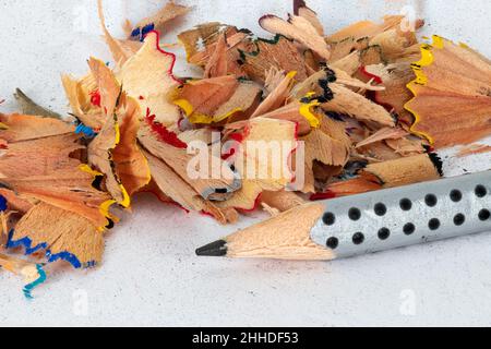 Sharpened black pencil with colored sharp waste on a white background Stock Photo