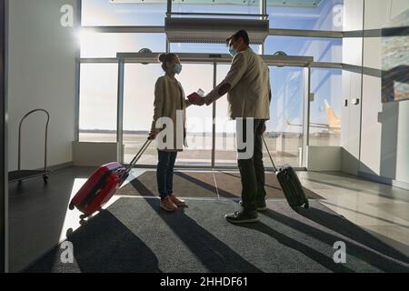 Romantic couple holding hands while standing inside airport Stock Photo