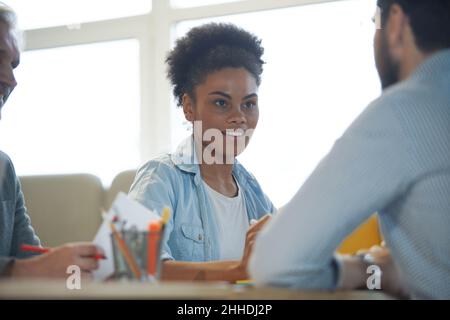 Happy young businesswoman coach mentor leader laughing at funny joke at group business meeting, joyful smiling millennial lady having fun with diverse Stock Photo