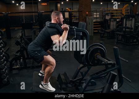 Male athlete doing squats using fitness equipment Stock Photo