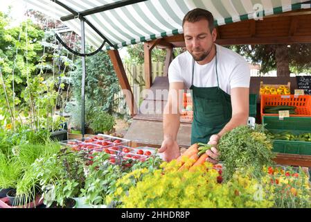 farmer sells fruit and vegetables from his own cultivation fresh from the field and from the greenhouse Stock Photo