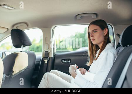 Tired female car passenger holding laptop in hands