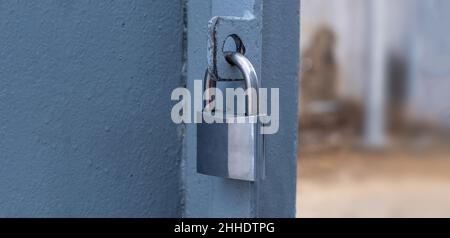 Heavy metal padlock on an open entrance gate, closeup view, banner. Stock Photo