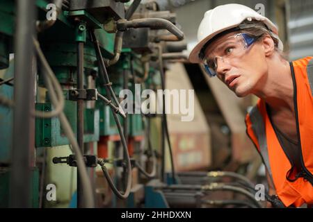 Professional engineer metalworker operating CNC milling machine center in manufacturing workshop Stock Photo