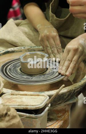 Pottery. Sculpt dishes from clay. Modeling of pots. Dirty hands of the master close-up in clay. Hobby Stock Photo