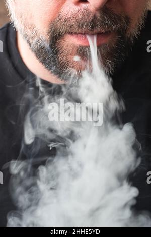 Close-up of a mouth blowing out gray cigarette smoke Stock Photo