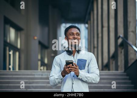 Young african american man happy with win looks at phone rejoices and smiles in casual clothes Stock Photo