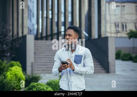 Young african american man happy with win looks at phone rejoices and smiles in casual clothes Stock Photo