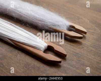 Soft pale pink woolen yarn on the weaving shuttles, close up. Tools for weaving with a loom Stock Photo