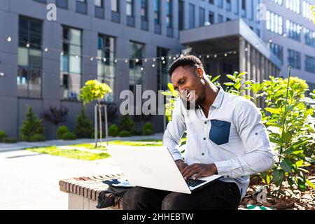african american male freelancer working remotely online broker with exchanges stocks talking on mobile phone and laptop Merchant seller. Male in city Stock Photo
