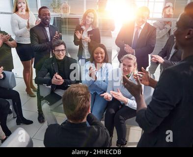 Office employees sit on chairs clap hands greeting presenter or speaker at group meeting close up. Stock Photo