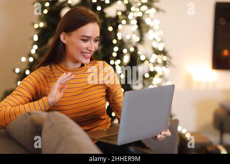 Smiling woman working on laptop waving hand Stock Photo